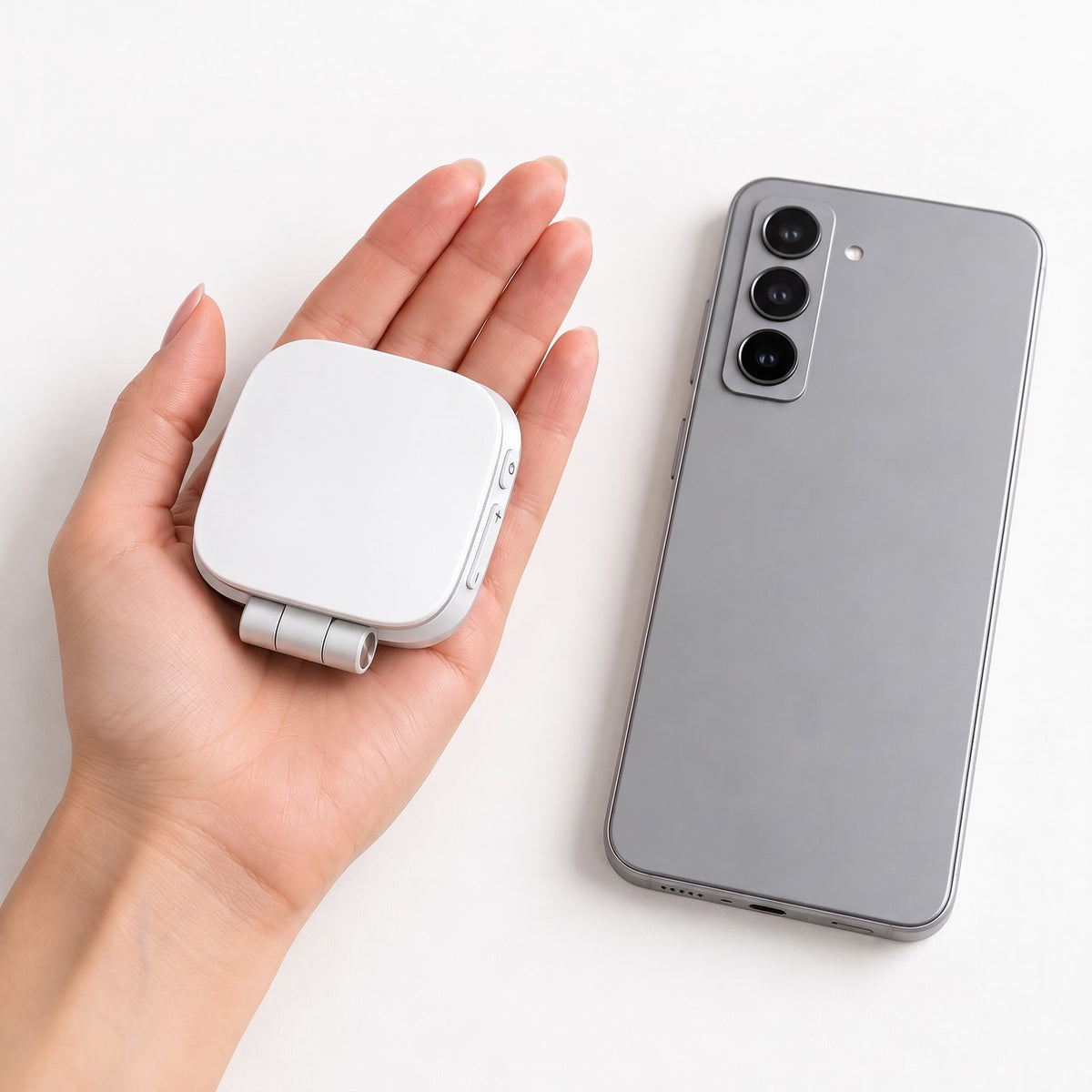 The closed white Studio light in an open palm next to a phone